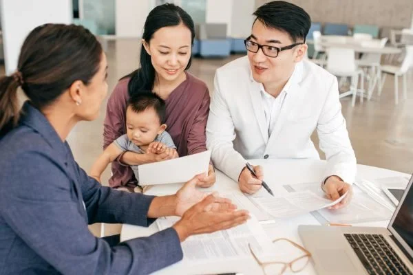 Young family meeting with a business advisor to discuss financial planning and family business goals, with documents and a laptop on the table.