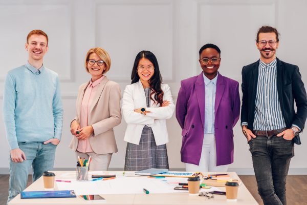 Portrait of a multiracial creative team of people in a modern office posing while looking into the camera. Group of diverse business people working together in the creative co-working space.